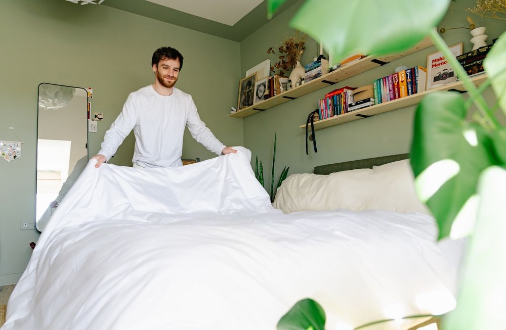 Making the bed in a plant-filled bedroom